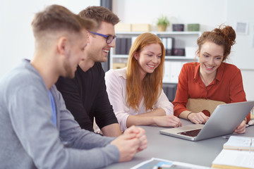 junges team schaut gemeinsam auf laptop