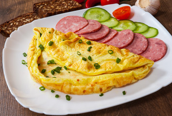 omelet with salami in a plate on wooden table