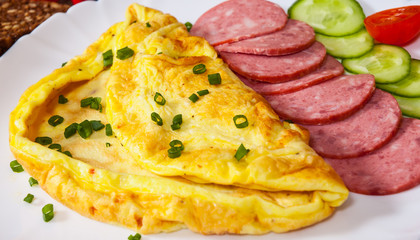 omelet with salami in a plate on wooden table