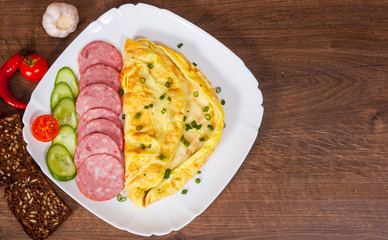omelet with salami in a plate on wooden table