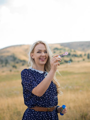 Portrait of a beautiful young woman blowing soap bubbles in the