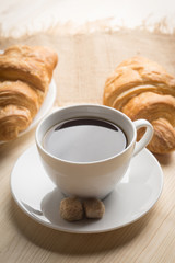 Croissants with cup of coffee on wooden background