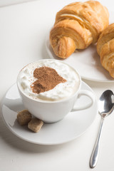 Croissants with cup of coffee on wooden background