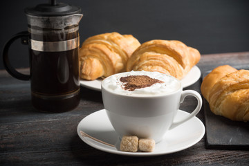 Croissants with cup of coffee on wooden background