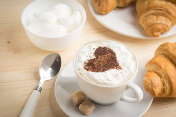 Croissants with cup of coffee on wooden background