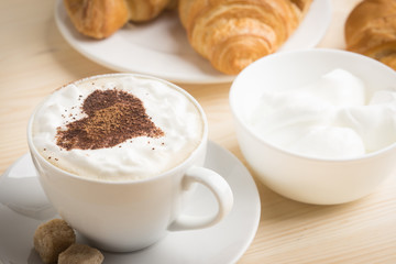 Croissants with cup of coffee on wooden background