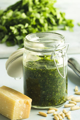 Bärlauchpesto in einem Glas mit geschnittenen Bärlauchblättern im Hintergrund