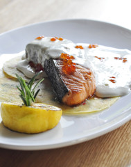 Close-up of salmon fillet steak served with sauce, herbs and lemon