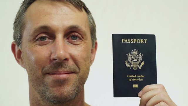 Closeup portrait shot of a happy middle aged male with an American passport ID which is needed to go on vacation or take business trips outside of the USA to other countries of the world.