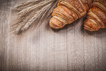 Golden wheat rye ears croissants on wooden board