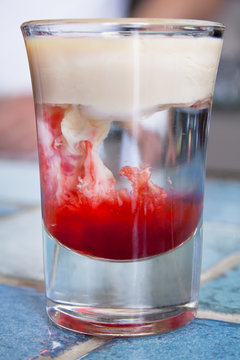 Monkey-brain cocktail in a shot glass on the bar - table with blue ceramic tiles.
