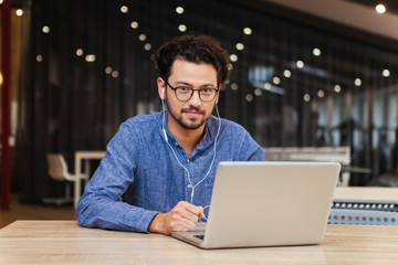 Handsome man sitting at the table with laptop in office