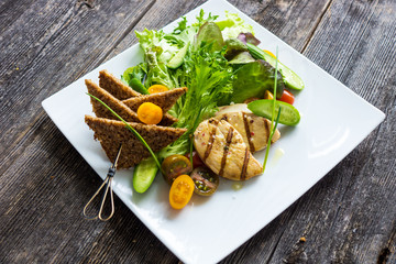 Delicious fresh salad with grilled chicken breast and crispy bread with seeds