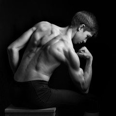 Fototapeta na wymiar Portrait of young and fit teen model posing his muscles in studio
