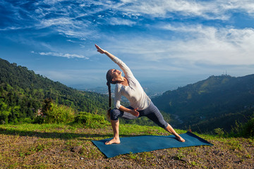 Woman practices yoga asana Utthita Parsvakonasana outdoors