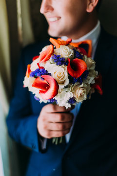 Closeup image of groom with wedding bouquet in a classic  blue costume. Wedding preparation