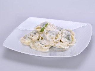 Closeup of a bowl of tortellini stuffed with spinach, four cheese sauce
