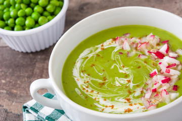 Peas cream with radishes on rustic wooden table
