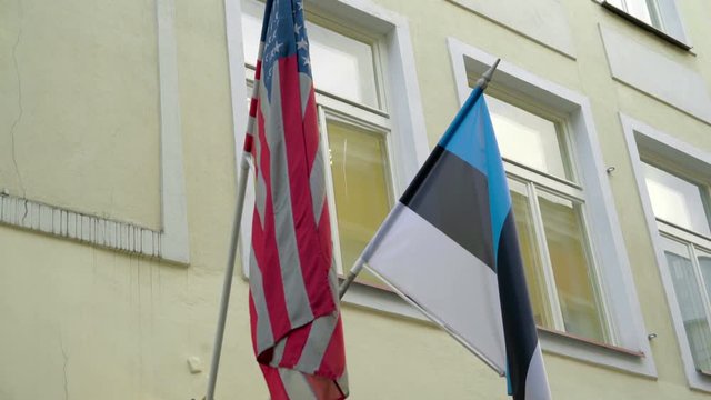 The flag of the USA and Estonia outside the building waving on the breeze of the wind