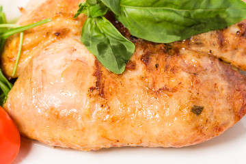 Grilled chicken fillet with fresh basil leaves.