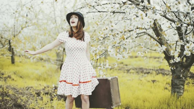 young woman dressed in retro style posing in blooming garden slow motion