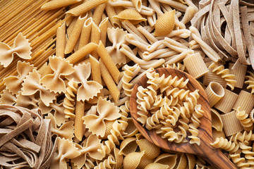 Variety of types and shapes of wholemeal pasta. Dry pasta background