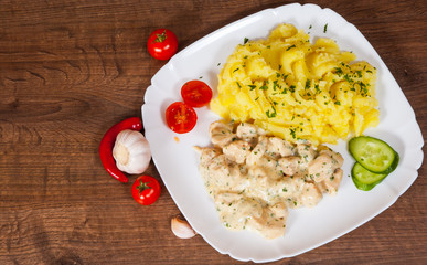 chicken breast in a creamy sauce with mashed potatoes in a plate on wooden table