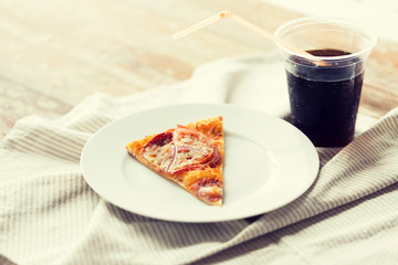 Pizza slice with cola soda drink on table