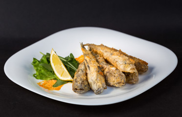Fried fish gobies in batter with lemon and greens