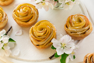 Fototapeta na wymiar Homemade apple rose cakes decorated apple blossom on white wooden desk