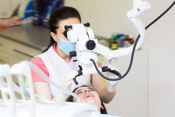 professional dentist examination patient with microscope at the office.Dentist looking through...