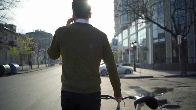 back view man goes near the bicycle and talks on the phone slow motion