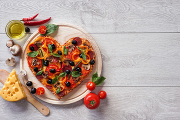 Savoureuse pizza en forme de coeur décorée de légumes et d& 39 herbes sur fond de bois blanc. Produit haute résolution.
