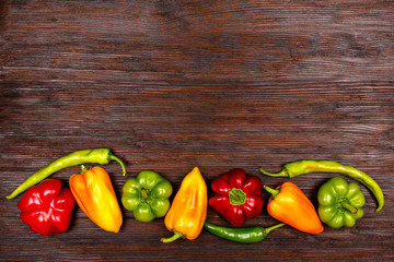 Different kinds of pepper on dark wooden background, top view