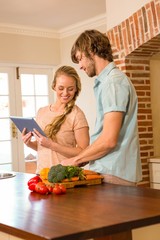 Cute couple cooking and using tablet