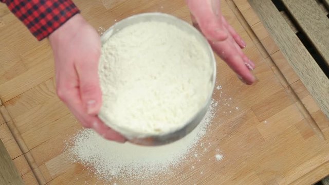 The chef sifts flour through a sieve. Preparing the dough on a wooden Board. Wheat flour.
