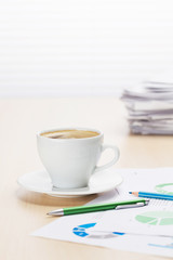 Office workplace with coffee, supplies and reports