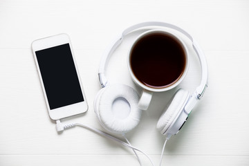 Fototapeta na wymiar Smartphone on white wood with headphone and cup of tea or coffee
