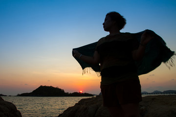 Fototapeta premium The silhouette of a woman in at twilight sunset on seashore, con
