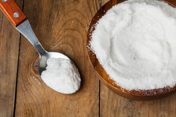 salt in bowl with spoon on the wooden table in kitchen