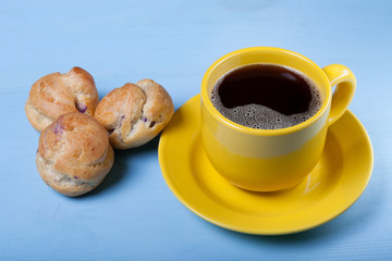 Fresh homemade profiteroles and cup of coffee on blue wooden tab
