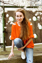 Young beautiful long-haired hipster girl on a sunny day outdoors in the city. Spring portrait of a...