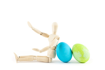 wooden doll sitting near Easter eggs on a white background