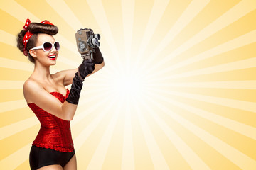 Retro movie style / Retro photo of a glamorous pin-up girl with an old vintage cinema 8 mm camera...