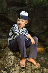 sailor boy sitting on a stone