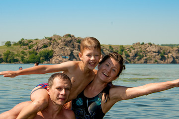 Fototapeta na wymiar Dad mom and son swimming in the river