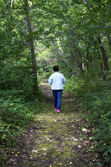 Naklejka na ściany i meble Senior woman walking down a forest path