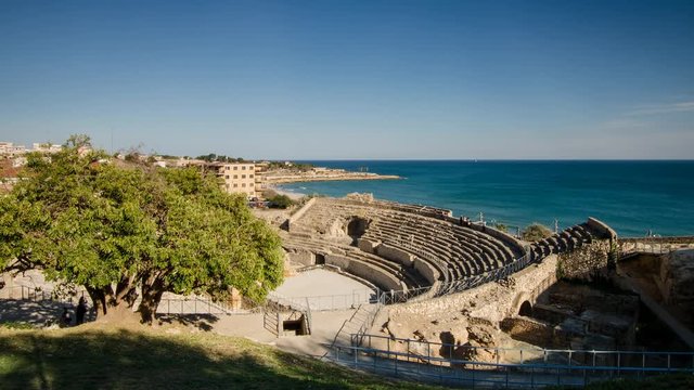 Timelapse of the Roman amphitheater of Tarragona (Catalonia) with the movement of Mediterranean sea in the background during a spring day without clouds.