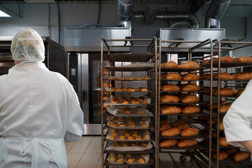 Racks of fresh loaves of bread and buns from ovens in Bakery