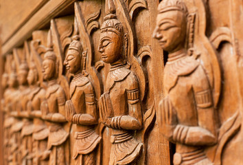 Carved wooden sculpture of praying Buddha in a line of different prayers